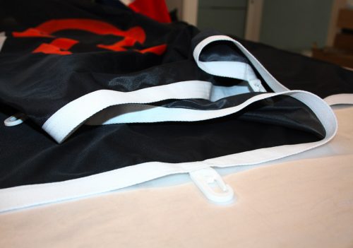 Bandiera personalizzata verticale - dettaglio tela di rinforzo bianca e moschettone in plastica.